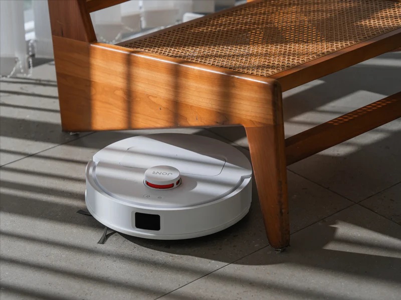 Biały robot JONR T5 Lite sprząta podłogę pod krzesłem